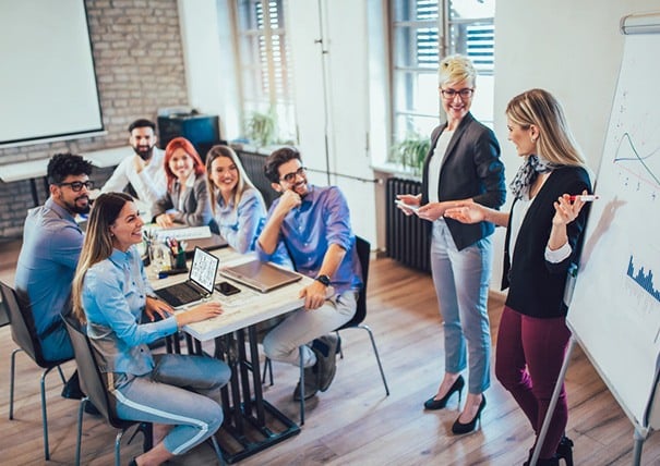 Zwei Frauen stehen an einem Flipchart und zeigen auf den Flipchart
Sechs Personen sitzen an einem Tisch und schauen auf den Flipchart